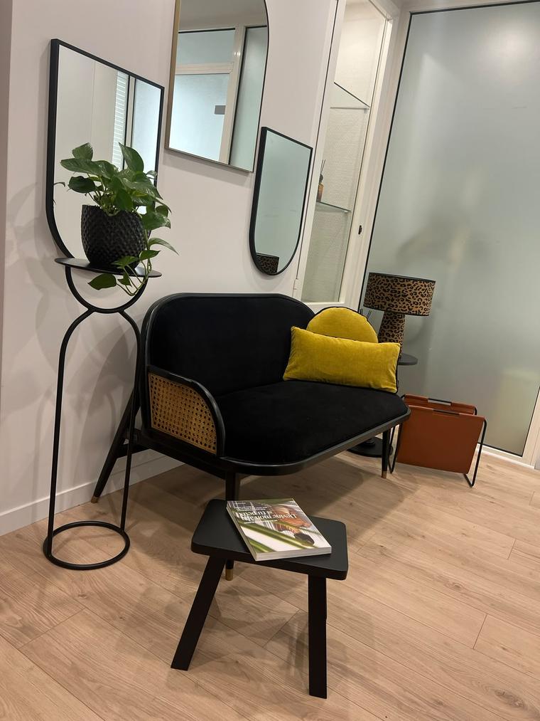 Deuxième salle d'attente privative : banquette noire, coussin jaune, miroirs et plante