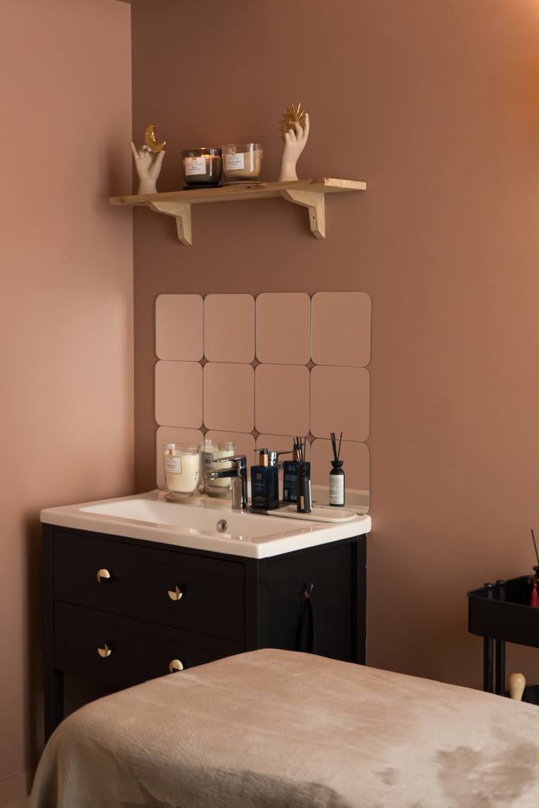 Coin lavabo de la salle de soin avec commode, miroir et bougies